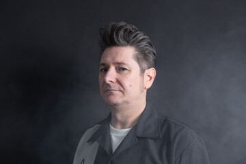Portrait of a man in his 50's with serious and confident expression, with nice hair, looking at camera surrounded by smoke. Dark background. Copy space. Concept of men, maturity and smoke