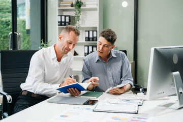 Two business workers talking on the smartphone and using laptop
