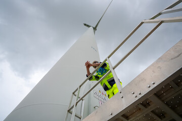Maintenance engineer working at wind turbine farm. Windturbine inspector wearing Personal protective equipment working at wind turbines farm