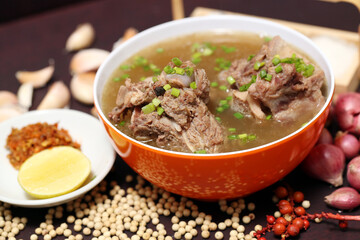 oxtail rib soup or Beef soup in red bowl with ingredients on wooden background, closeup photography  for banner menu restaurant, flyer poster designs, catalogue food dish