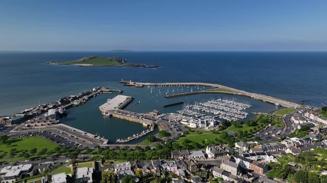 Howth Harbour, County Dublin, Ireland, May 2023. Drone panoramic overview with a slow push forward above Yacht Club and Marina with Ireland's Eye and Lambay Island in the distance.