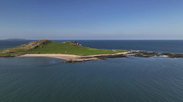 Ireland's Eye, County Dublin, Ireland, May 2023. Drone orbits clockwise around the Island on a bright sunny day showcasing a panoramic view of the beach with Lambay Island in the distance.