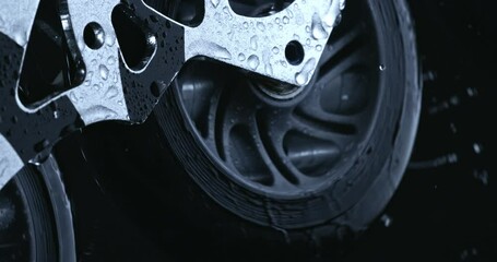 Super slow motion macro of wet inline roller sports skates wheels rotating with energetic movement with splashing water drops isolated on dark background at 1000 fps. - Powered by Adobe