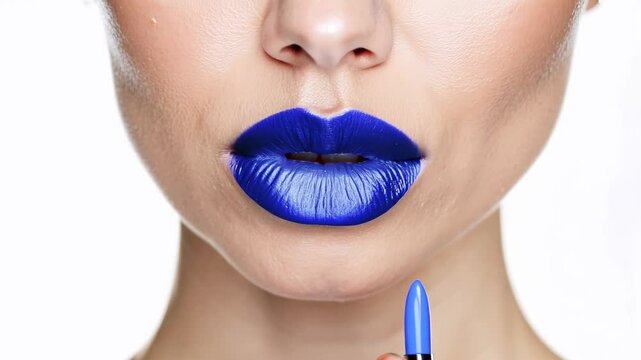 woman applying vibrant blue lipstick, highlighting a bold and unconventional makeup look, ideal for artistic or fashion-forward expressions