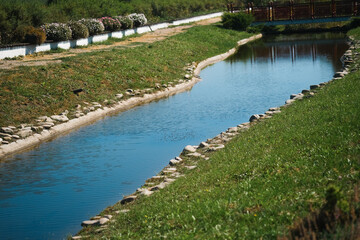 Calm river with clear blue water flowing through a green landscape under bright sunlight