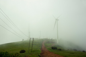 A foggy path with windmills and electric poles