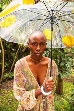 A young black, bald woman holding an umbrella 