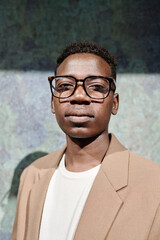 Fototapeta premium Vertical medium closeup of young African American male CEO wearing eyeglasses standing outdoors and looking at camera