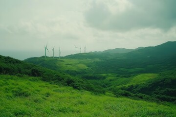 Lush green hills with wind turbines under a cloudy sky, serene landscape view.