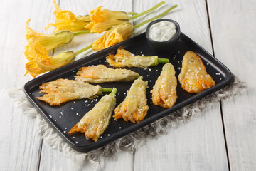 Fried zucchini flowers stuffed with cream cheese closeup on the plate on the table. Horizontal