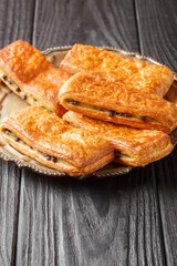 pain suisse au chocolat French buns with custard and chocolate drops close-up in a plate on a table. Vertical