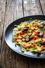 Vietnamese pizza - rice pepper omelet with mushrooms chicken meat and fresh vegetables served  on black plate on wooden table
