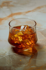 Glass of liquor scotch whiskey and ice cubes on luxury granite table top. Space for text