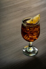 Glass of liquor scotch whiskey with lemon and ice cubes on wood table top. Space for text