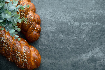 Homemade challah, traditional braided bread loaf with poppy and sesame seeds on a concrete background. Overhead shot of freshly baked challah bread. Concept of festive baking. space for text. top view
