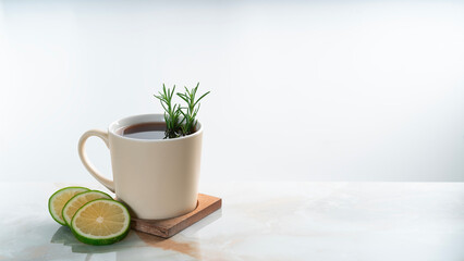 a mug of hot lemon tea with rosemary on granite table.