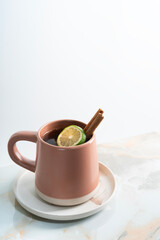 Vertical view a mug of hot lemon tea with cinnamon on granite table.