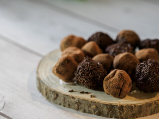 Delicious chocolate truffles on wooden tray and white background