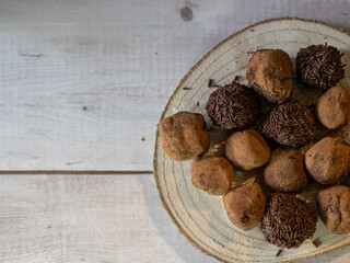 Top view of delicate chocolate truffles on wooden plate and white background