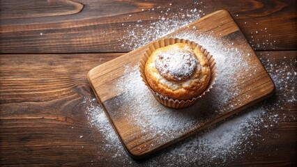Flaky pastry muffin dusted with powdered sugar on wooden cutting board aerial view