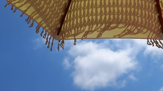 Time lapse delle nuvole che passano veloci sopra un ombrellone per il sole, ricamato all'uncinetto