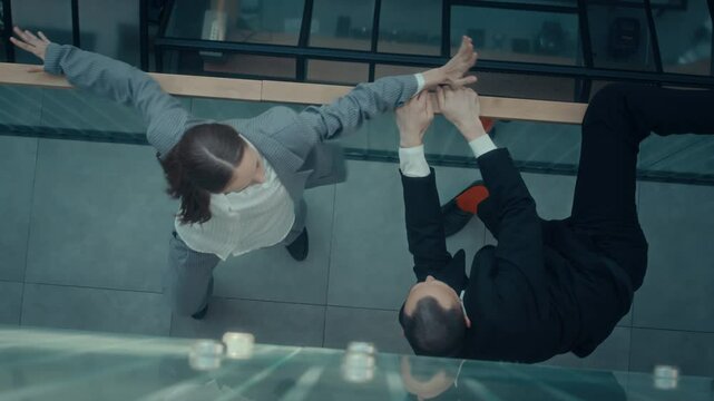 Top down view shot of modern business couple performing contemporary dance by glass railing in contemporary business centre