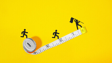 Fitness trainer instructor motivates his wards on workout. Measuring tape on yellow background with copy space. Weight loss marathon. Coach motivates to growth