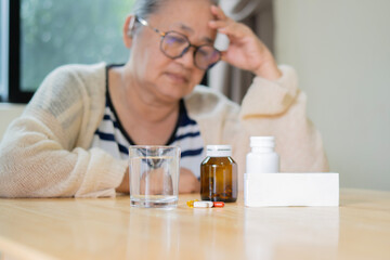 Senior hispanic grandmother sitting at kitchen table with daily medicine, copy space.