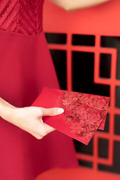 Hand of woman holding red envelope near door
