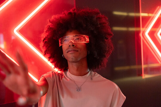 Young man with curly hair wearing red smart glasses