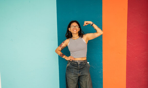 Happy woman flexing muscles near striped wall