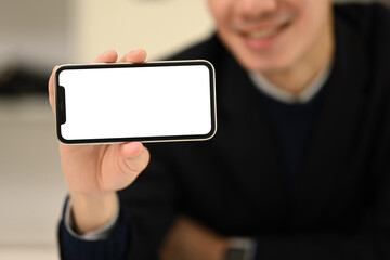 Smiling young man holding a smartphone with a white screen