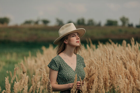 Beautiful woman with hat standing amidst reeds on sunny day