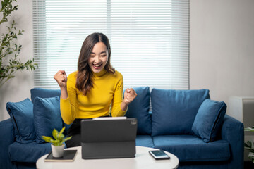 Young businesswoman celebrating success while working at home using tablet © Wasana