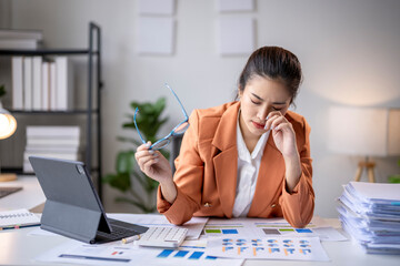 Asian accountant woman feeling tired and stressed working on financial documents at office desk