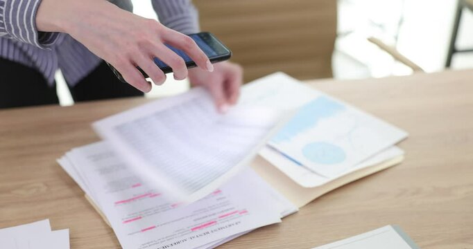 Marketing manager scanning business documents using phone at table