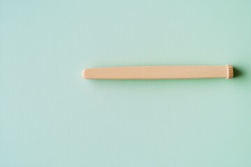 Simple wooden stick placed on a soft blue green background showcasing minimalist aesthetics in design