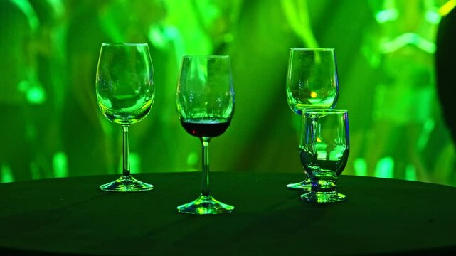 Wine Alcohol Glasses Left Unattended on Table at Disco Club by Dance Floor with People Dancing and Having Fun