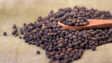 Side angle of black pepper on a wood spoon