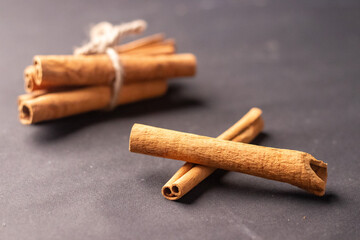 cinnamon sticks tied with a string on a wooden table in a wooden bowl kept on a black background