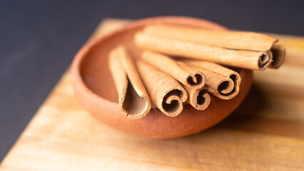 cinnamon sticks in a wooden bowl kept on a black background