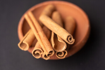 cinnamon sticks in a wooden bowl kept on a black background