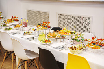 A served festive table with a variety of appetizers and flowers in a vase. catering for a banquet.