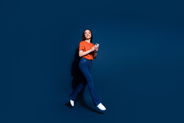 Naklejka premium Photo of lovely adorable cheerful woman wear orange stylish clothes hold device go store isolated on dark blue color background