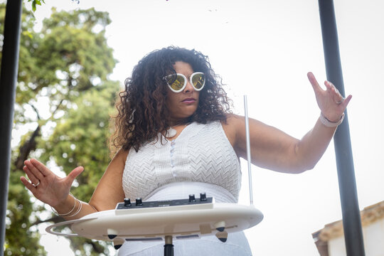 Elegant Woman in White Dress Giving a Theremin Concert in Garden Setting