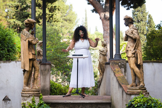 Elegant Woman in White Dress Giving a Theremin Concert in Garden Setting