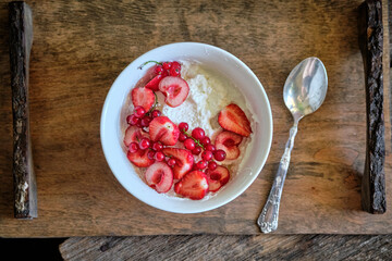 Bowl with cottage cheese, cream, strawberries, red currants and cherries