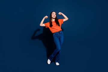Photo of strong funny woman wear orange stylish clothes look empty space poster isolated on dark blue color background