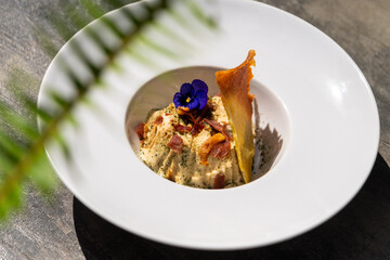 A savory vegetable flan served with thin slices of prosciutto crudo and crispy polenta. This elegant dish combines rich flavors and textures for a gourmet presentation.