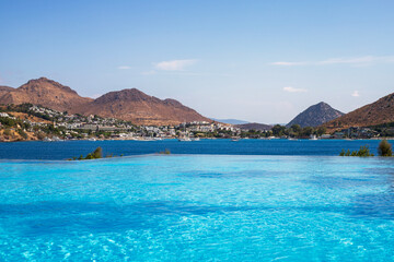 Obraz premium Magnificent view of turquoise water pool and dark blue Aegean sea near luxury Turkish hotel in Akyarlar area of ​​Bodrum province, Turkey.
